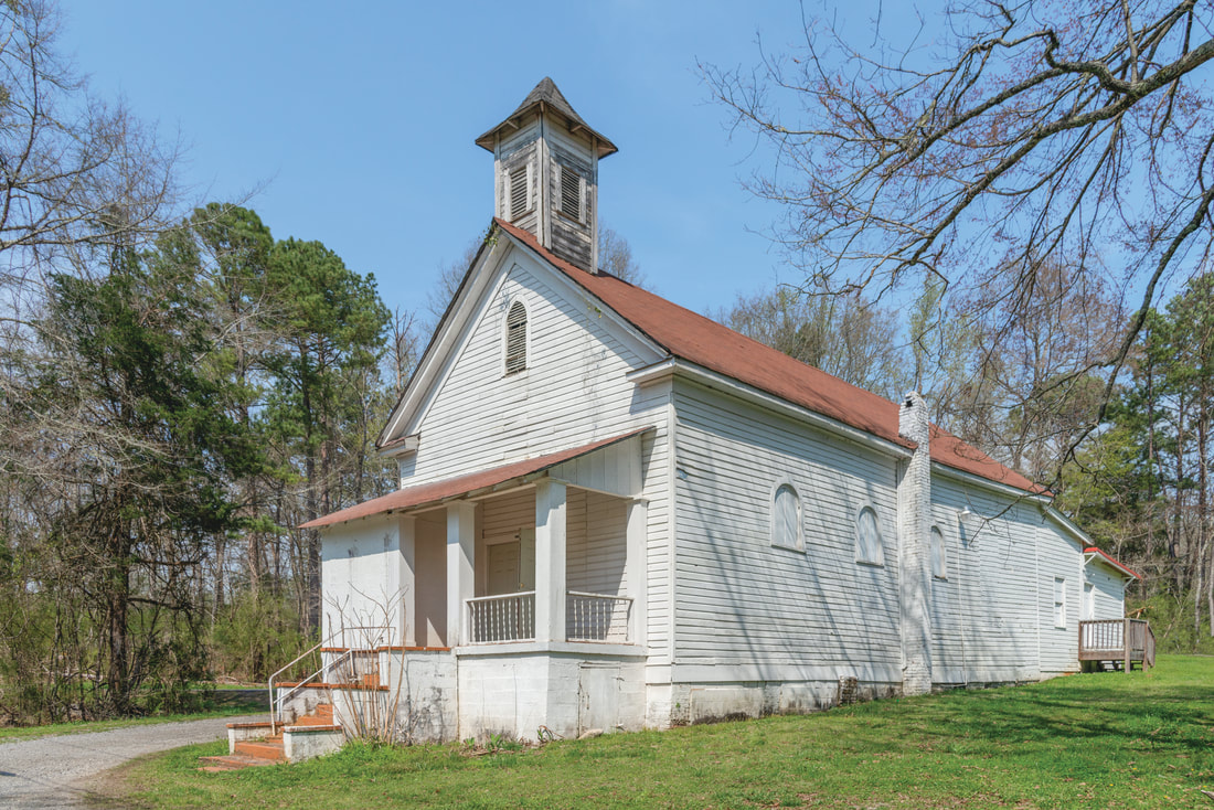 A white church with a tan roof is shown.